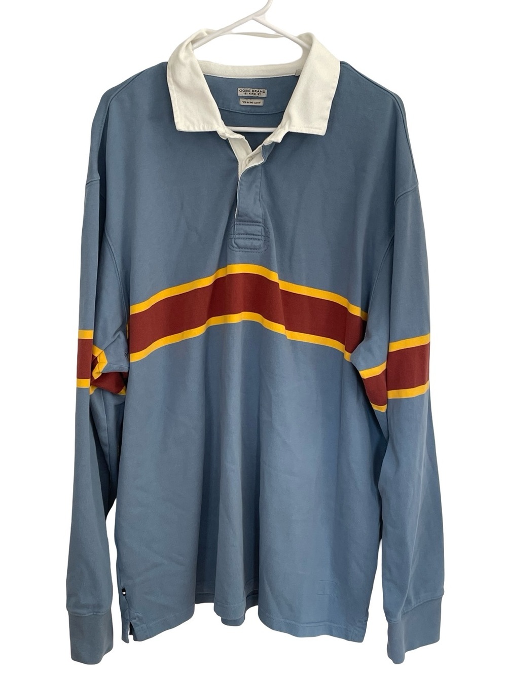 Oobe rugby shirt featuring a white collar and burgundy and yellow stripes.